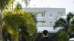 Un couple se promène sur un sentier qui mène à un bâtiment portant l’inscription « COURTYARD BY MARRIOTT ».