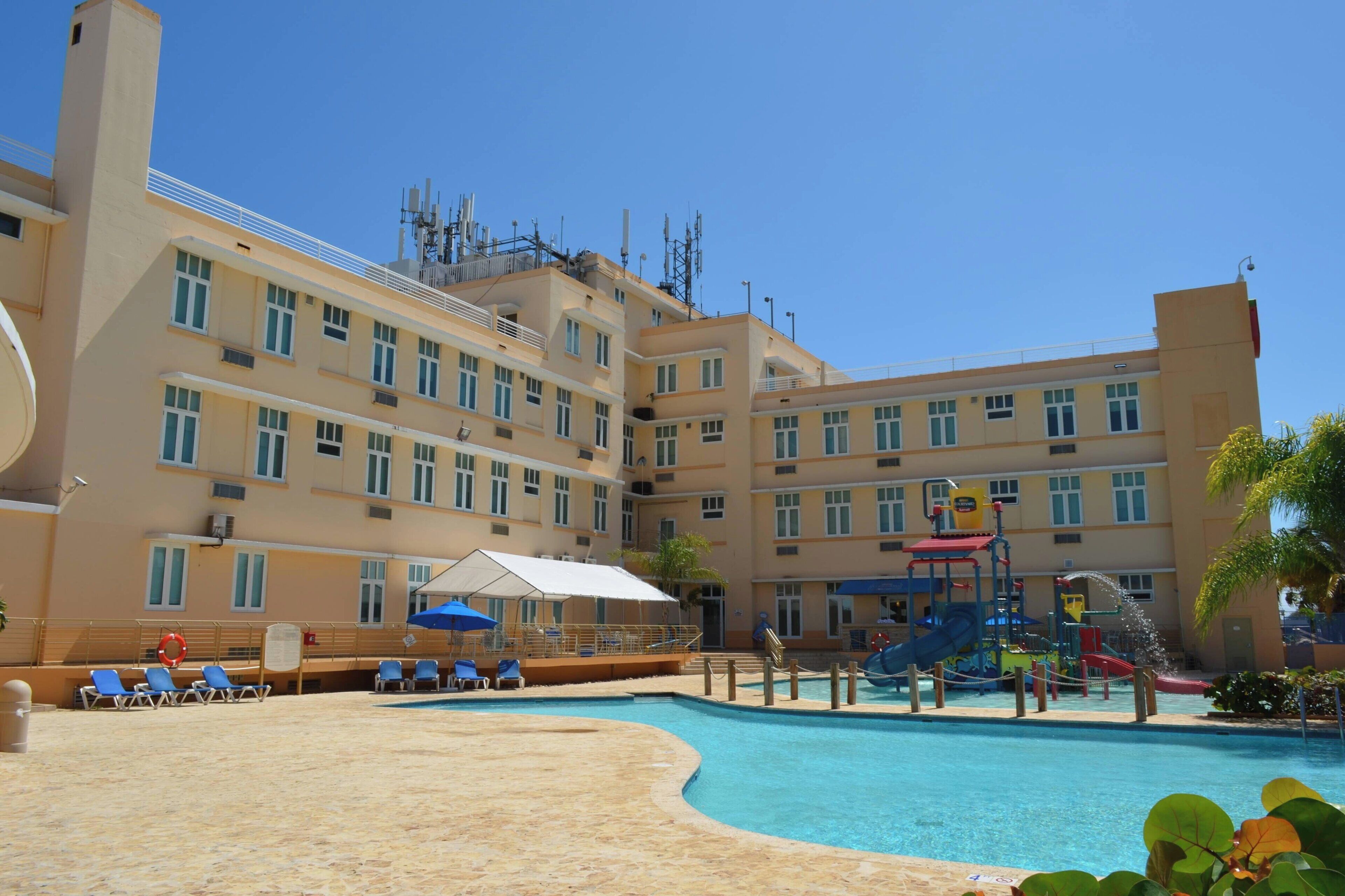 Ένα ξενοδοχείο με πισίνα, ξαπλώστρες και παιδότοπο.