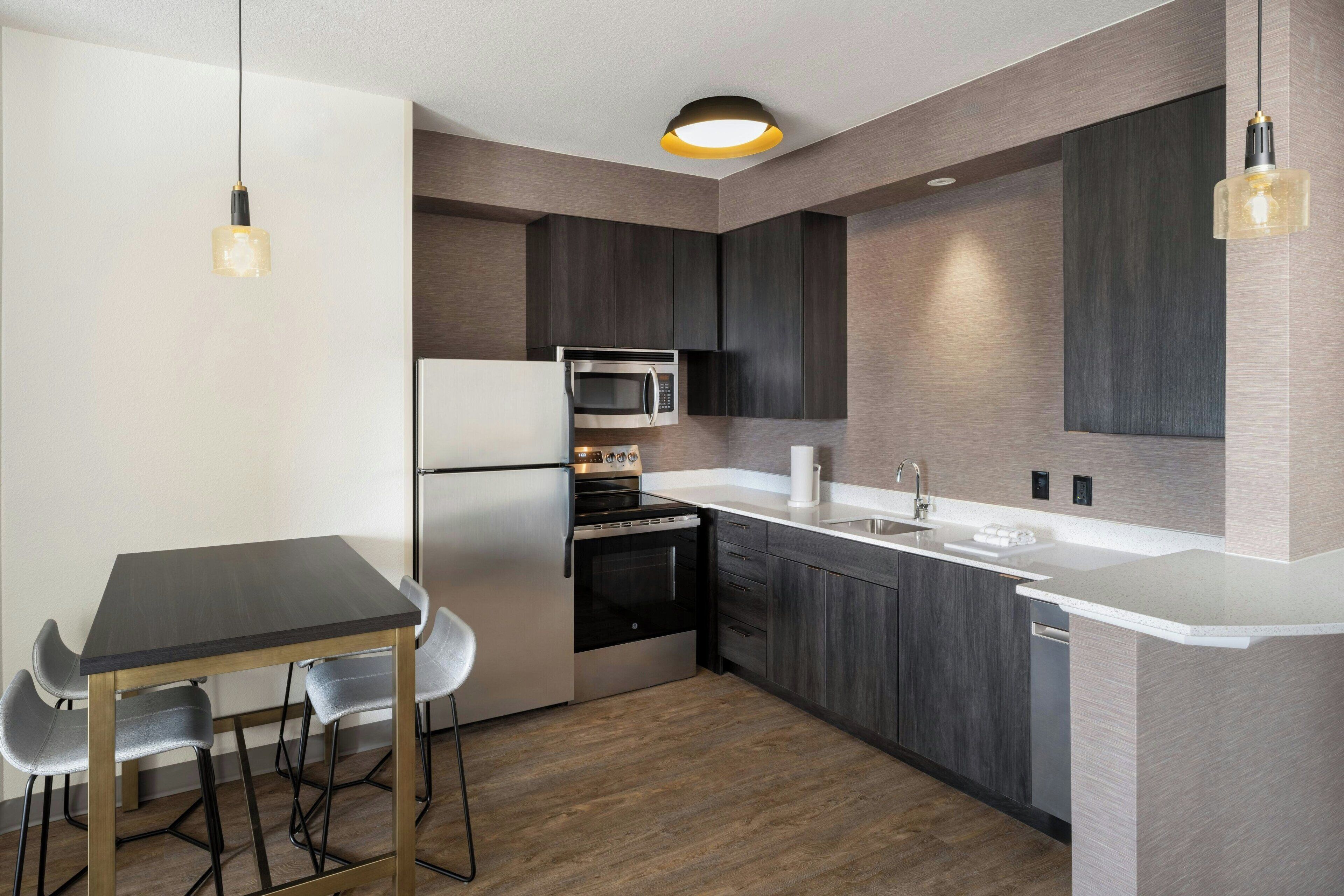 A modern kitchen with a dining area, stainless steel appliances, and a white countertop.