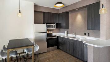A modern kitchen with a dining area, stainless steel appliances, and a white countertop.