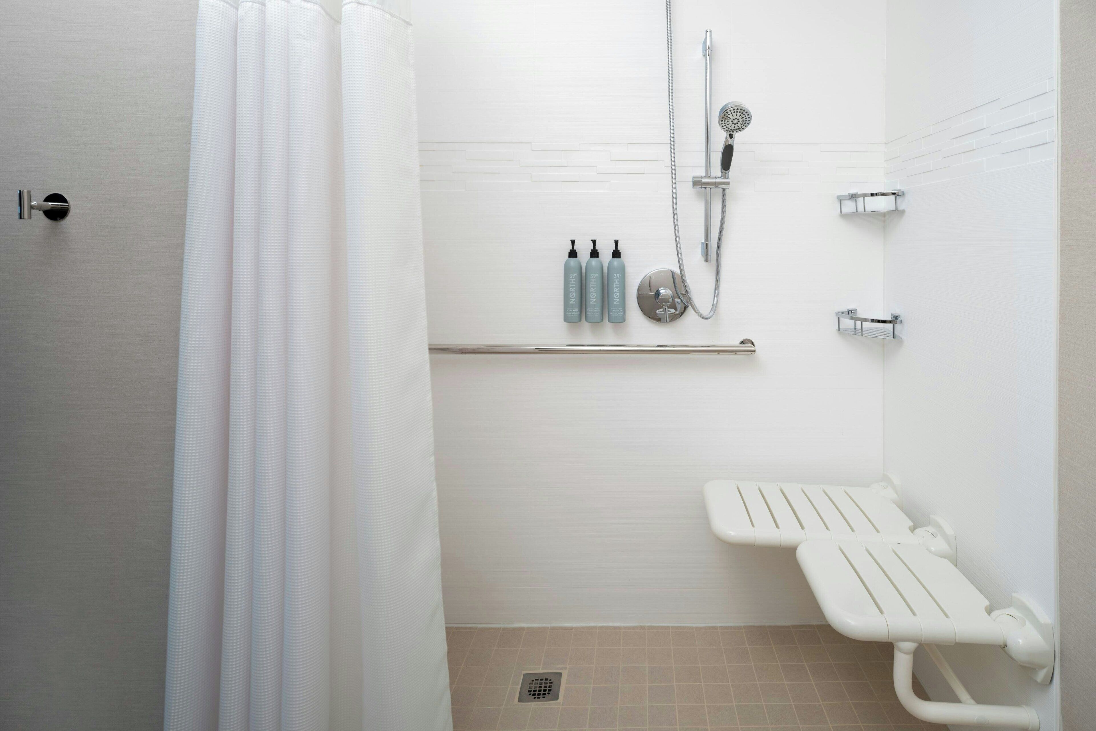Un baño moderno con ducha, inodoro y un banco.