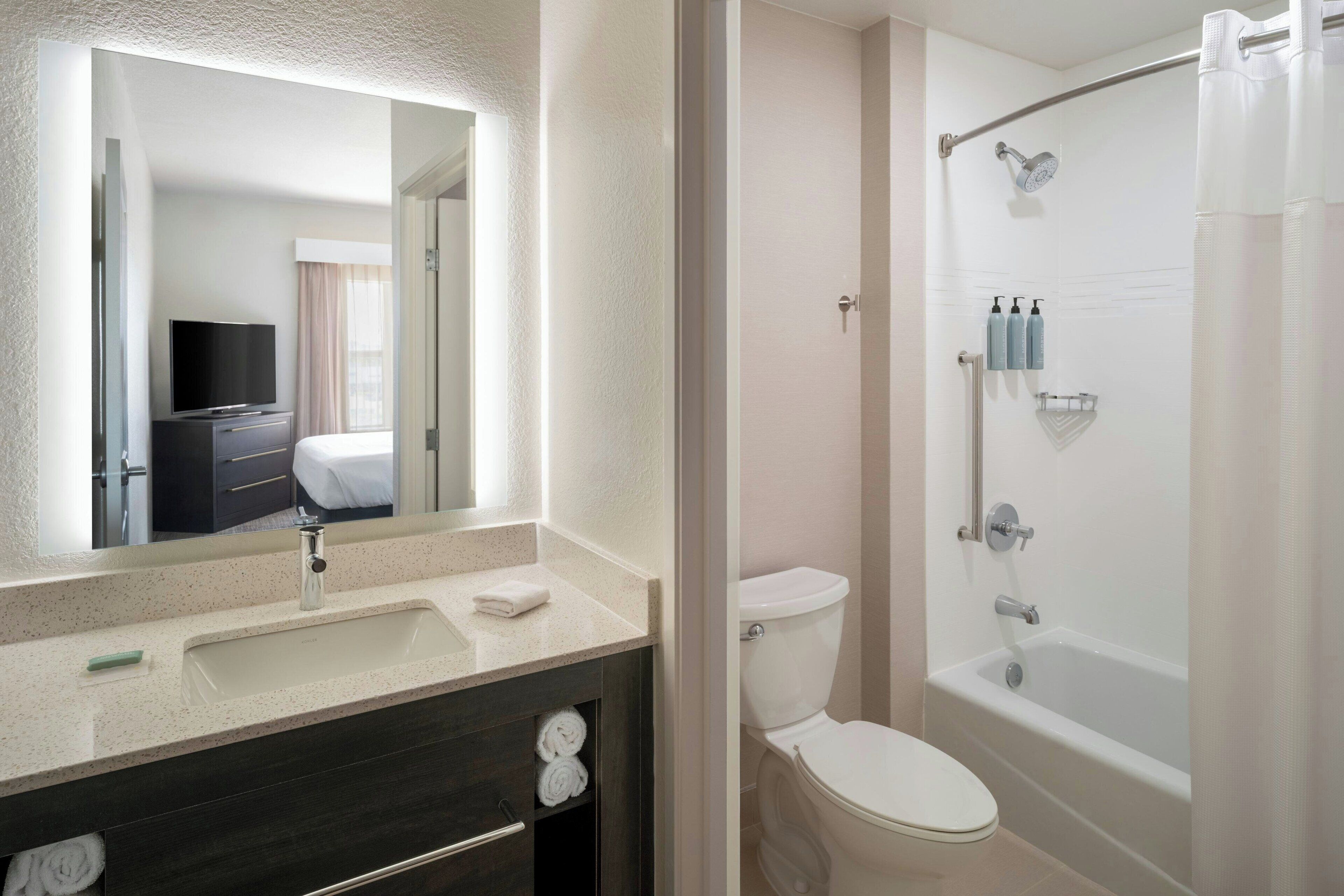 Un baño moderno con lavamanos, espejo, inodoro y bañera.