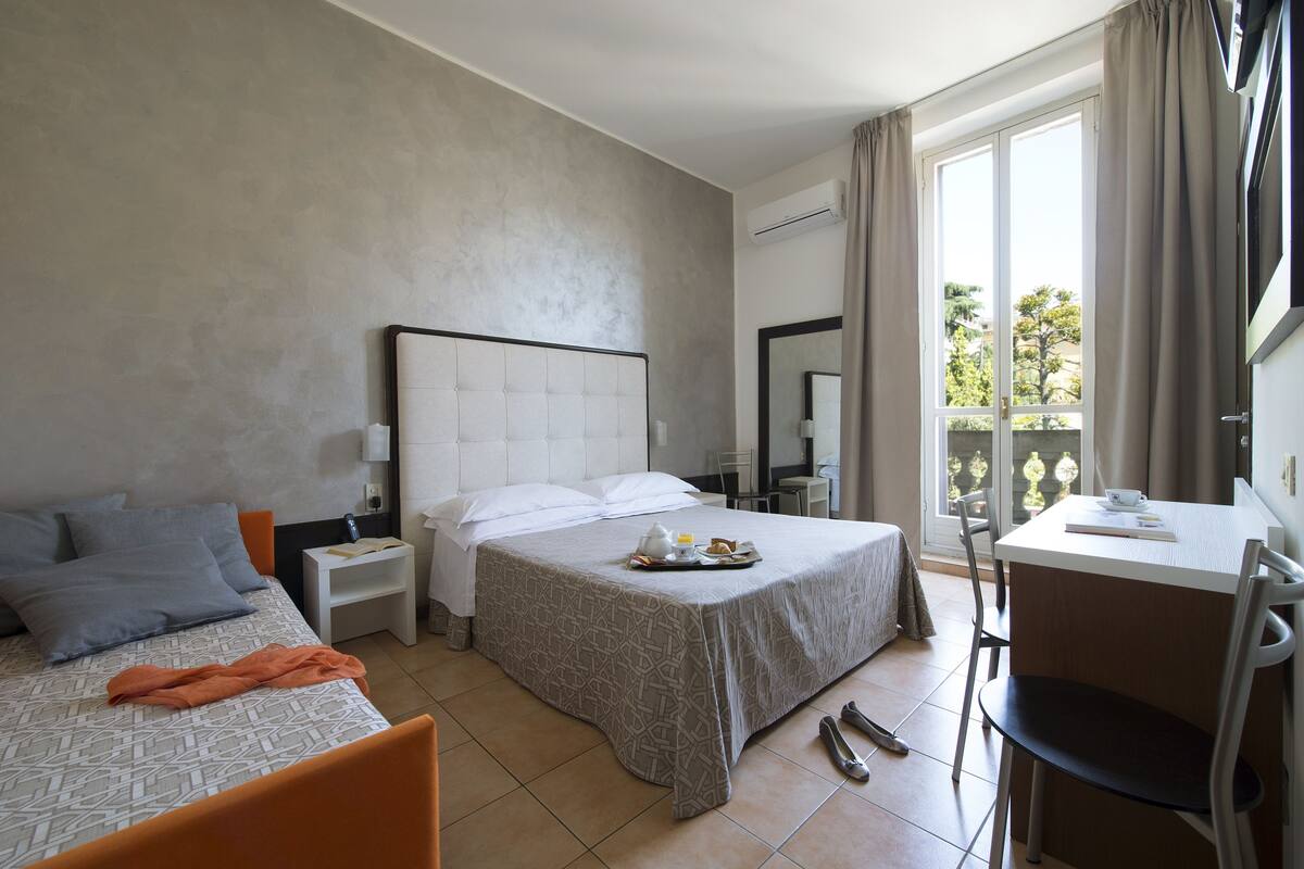 Een hotelkamer met een bed, een bureau en een balkon.