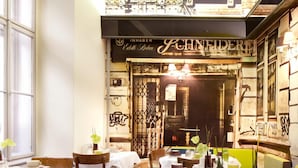 A restaurant interior with tables set for dining, a visible menu board, and a decorative wall with text. - Saint Shermin (Vienna)