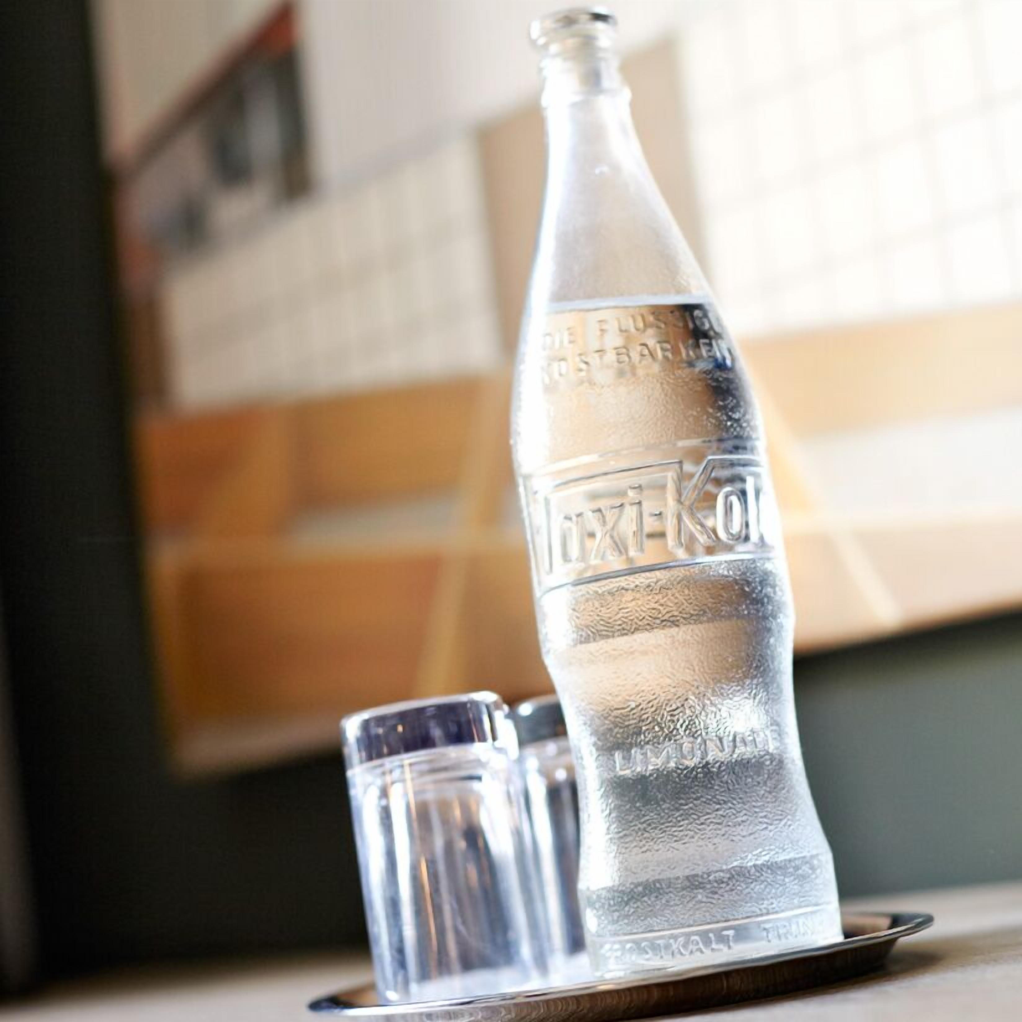 Eine klare Glasflasche mit Etikett und ein kleines Glas mehr auf einem Tablett.
