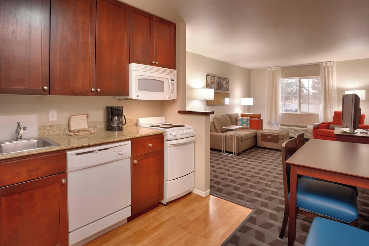 A compact kitchen with a microwave, stove, and dishwasher. There is a dining area with a table and chairs.