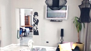 A modern living room with a sectional sofa, a flat-screen TV, and decorative lighting.