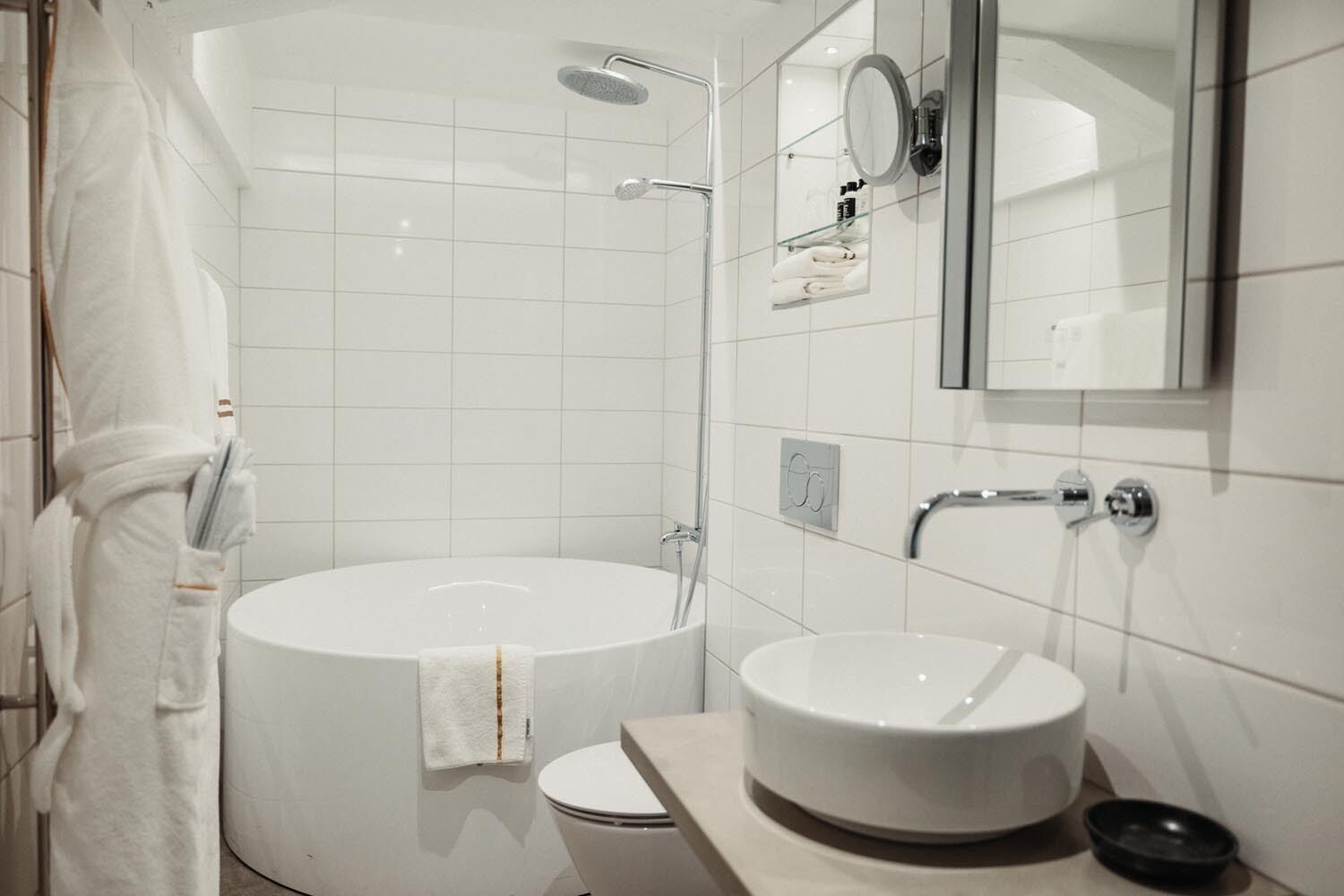A modern bathroom with a freestanding bathtub, a round sink, and a toilet.