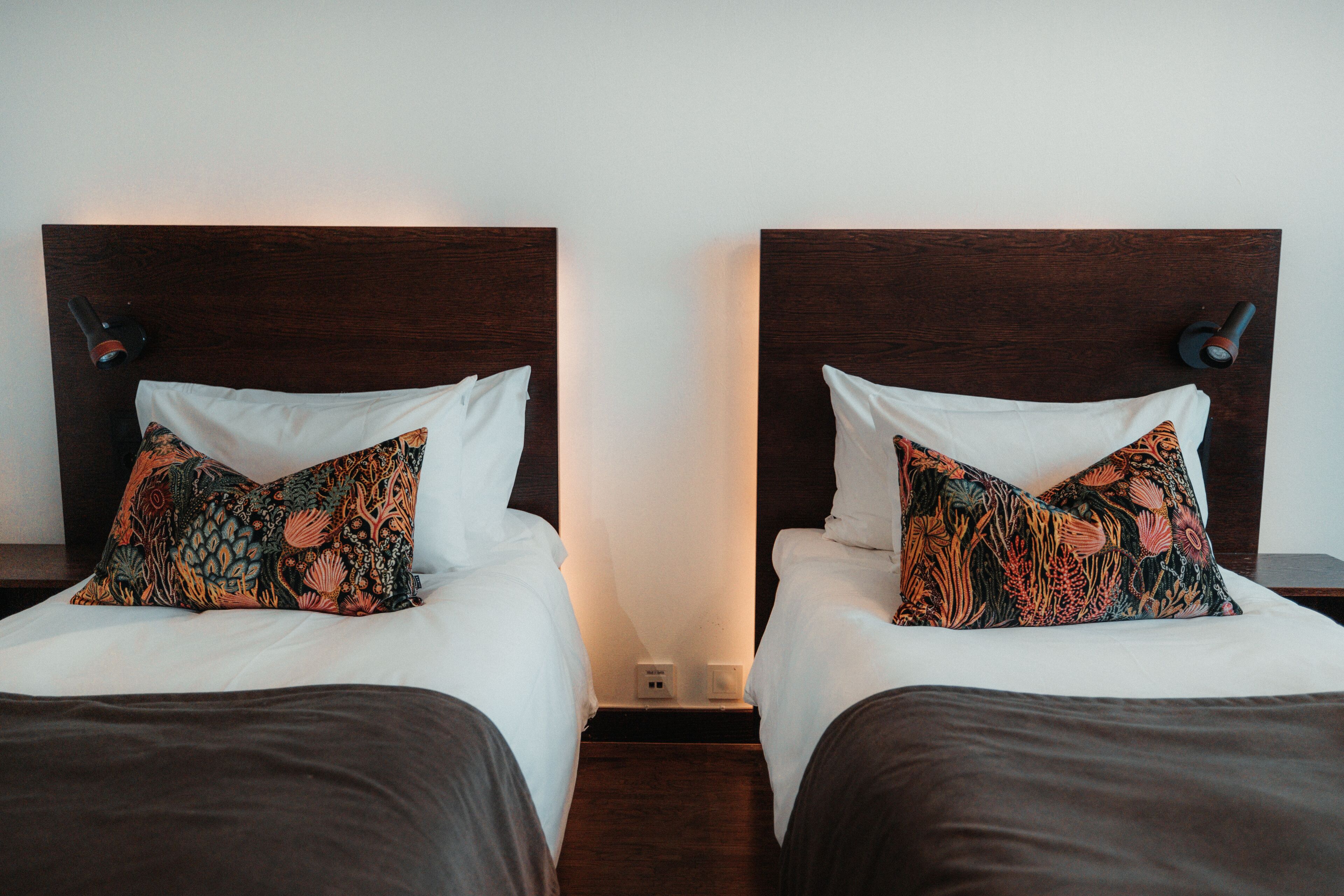 Two twin beds with matching headboards, white bedding, and patterned pillows.