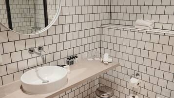 A modern bathroom with a white sink, mirror, and tiled walls.