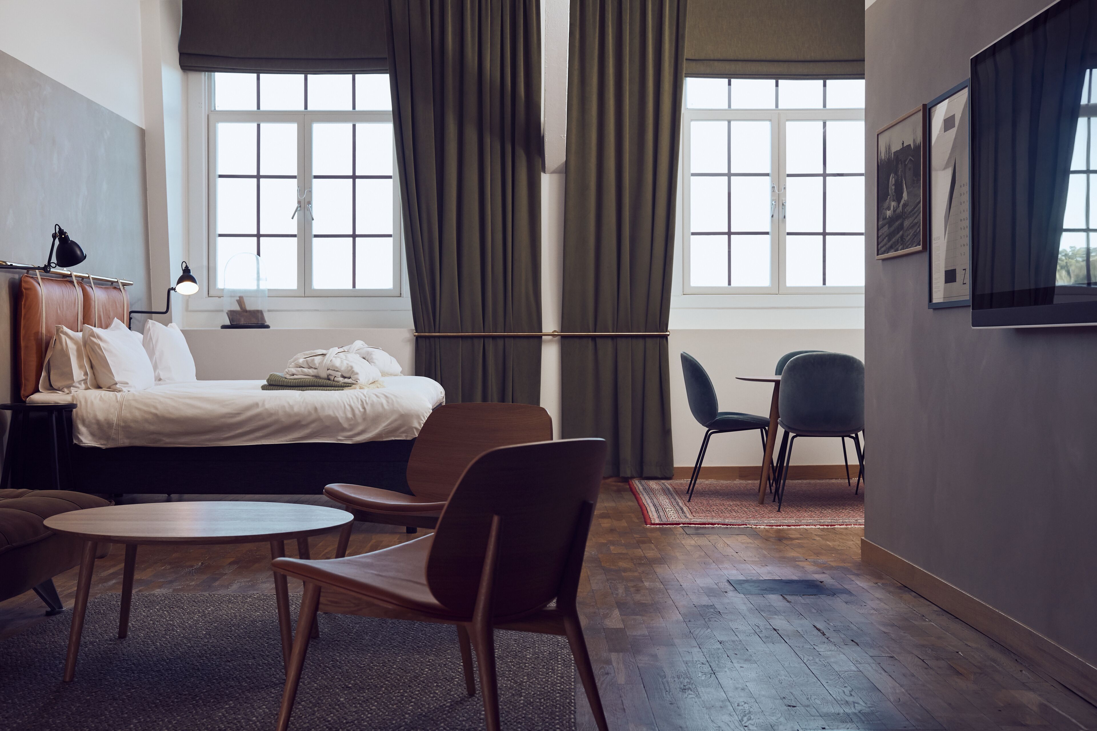 Habitació d'hotel amb un llit, una taula de treball, una cadira i una finestra amb cortines.