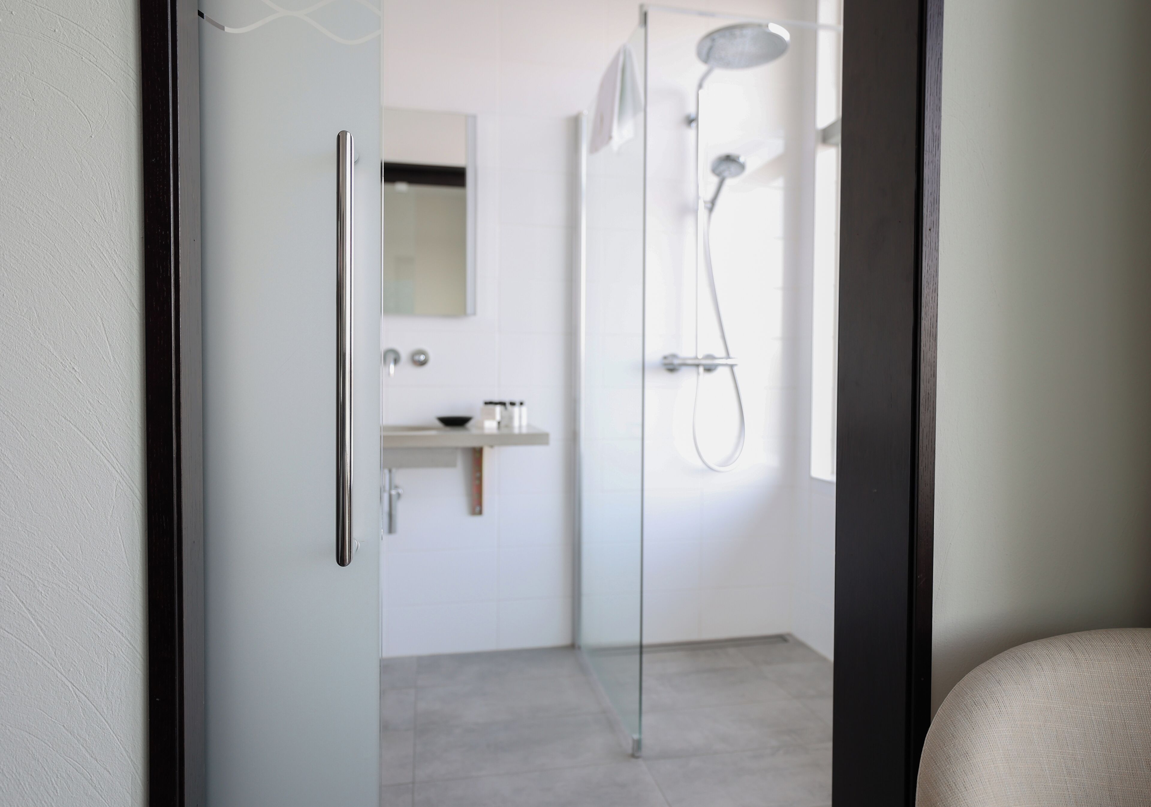 A modern bathroom with a glass shower enclosure, a white sink, and a mirror above it.