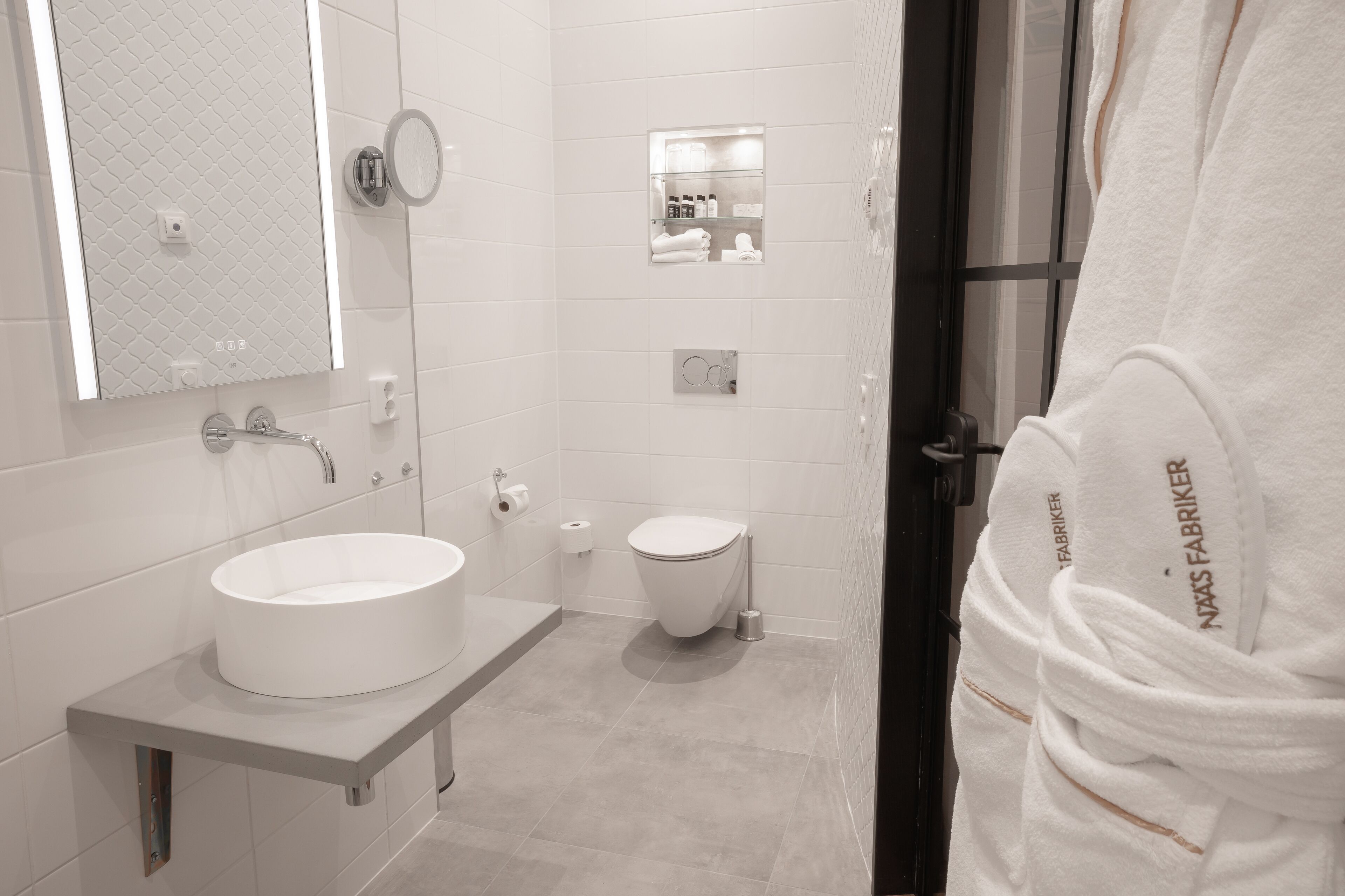 A modern bathroom with a round sink, a toilet, and a mirror.