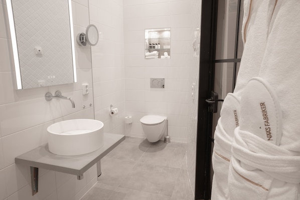 Un baño moderno con un lavabo redondo, un inodoro y un espejo.