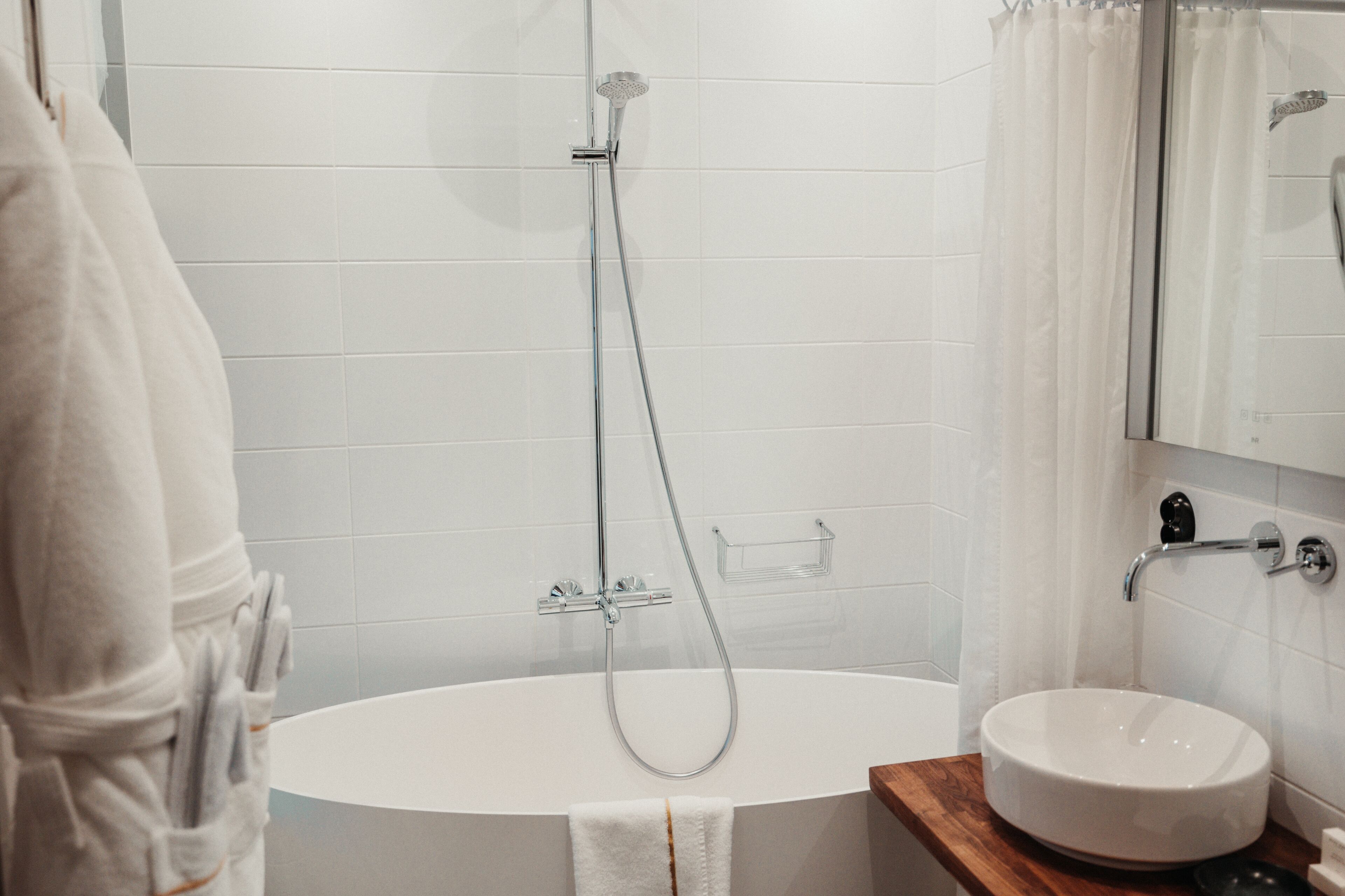 Un baño moderno con una bañera independiente, un lavamanos y un espejo.