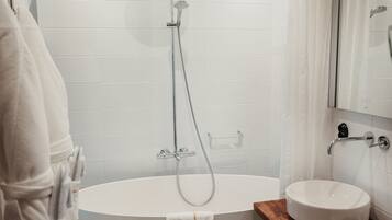 Un baño moderno con una bañera independiente, un lavamanos y un espejo.