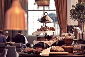 A buffet table with various breads, pastries, and a tiered bread display.