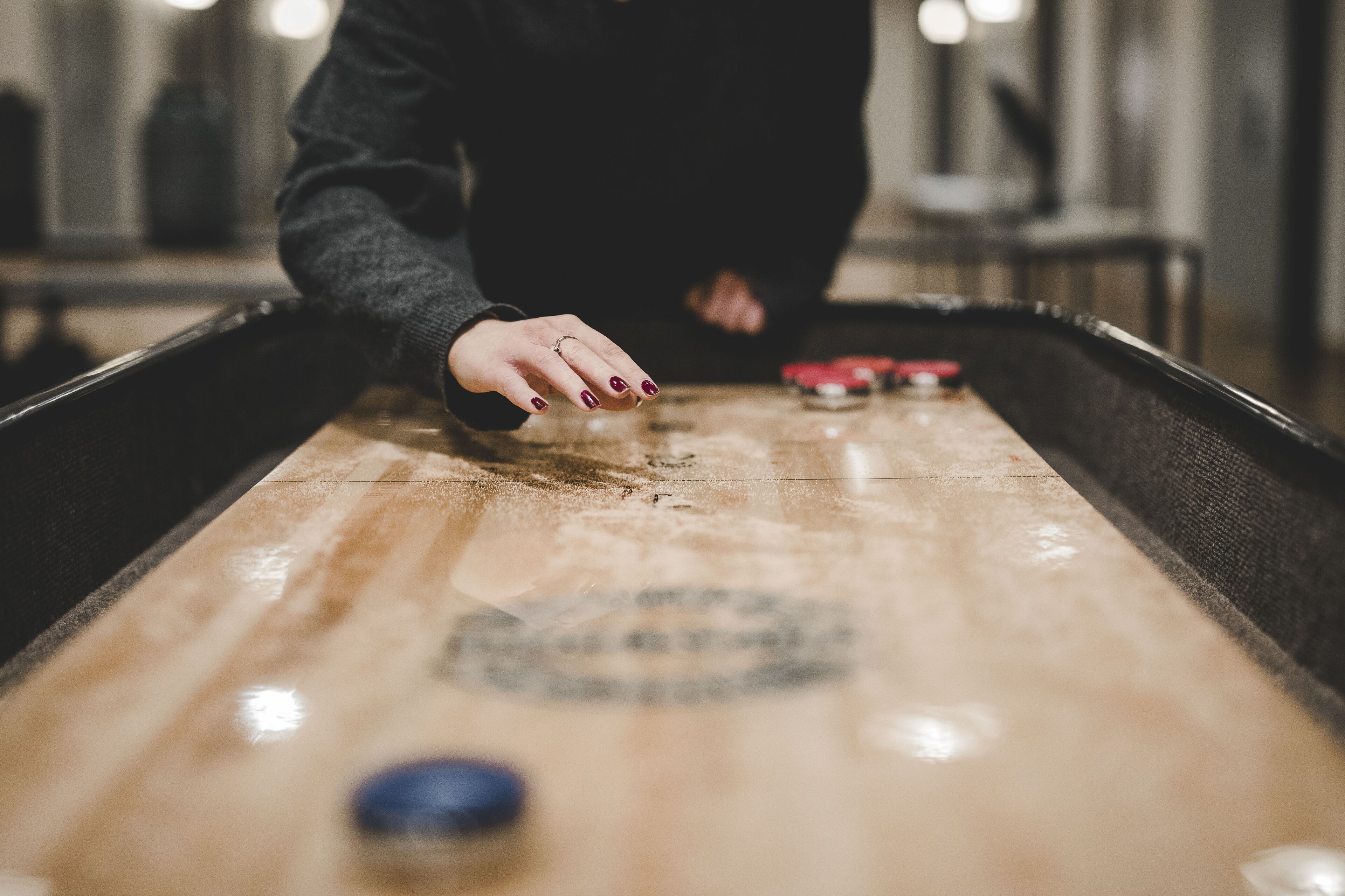 A close-up of a shuffleboard table with a puck in the foreground.