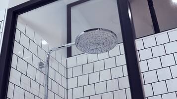 A shower with a glass enclosure and a tiled wall.