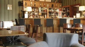 A bar area with a wooden counter, multiple chairs, and a dining table with a plaid tablecloth.