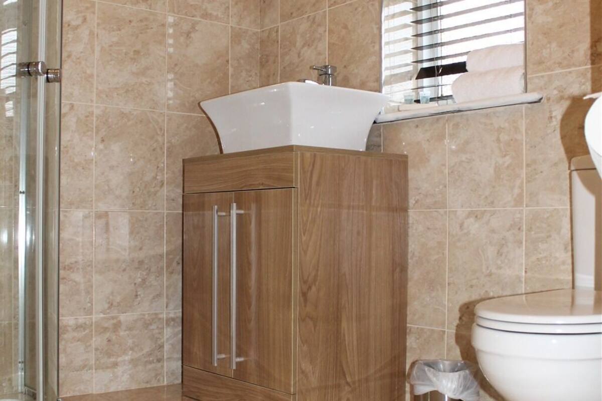 A bathroom with a wooden cabinet, a white sink, and a toilet.