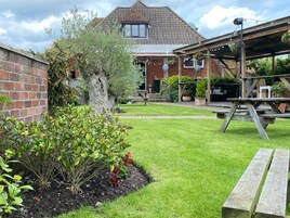 Une maison avec une façade en briques, une terrasse en bois et une pelouse bien entretenue.