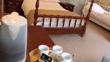 A hotel room with a wooden four-poster bed, a bedside table with a lamp, and a tray with cups and a teapot.