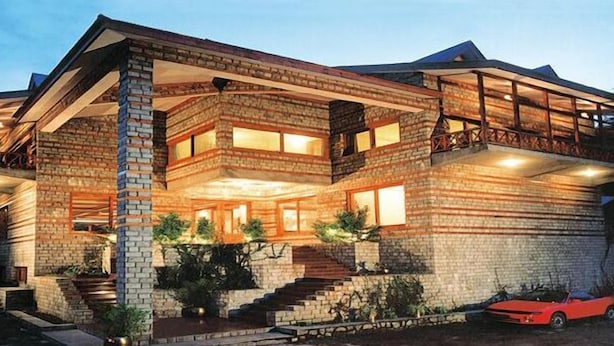 A multi-story house with a brick exterior, large windows, and a red car parked in front. - Banon Resorts (Manali)