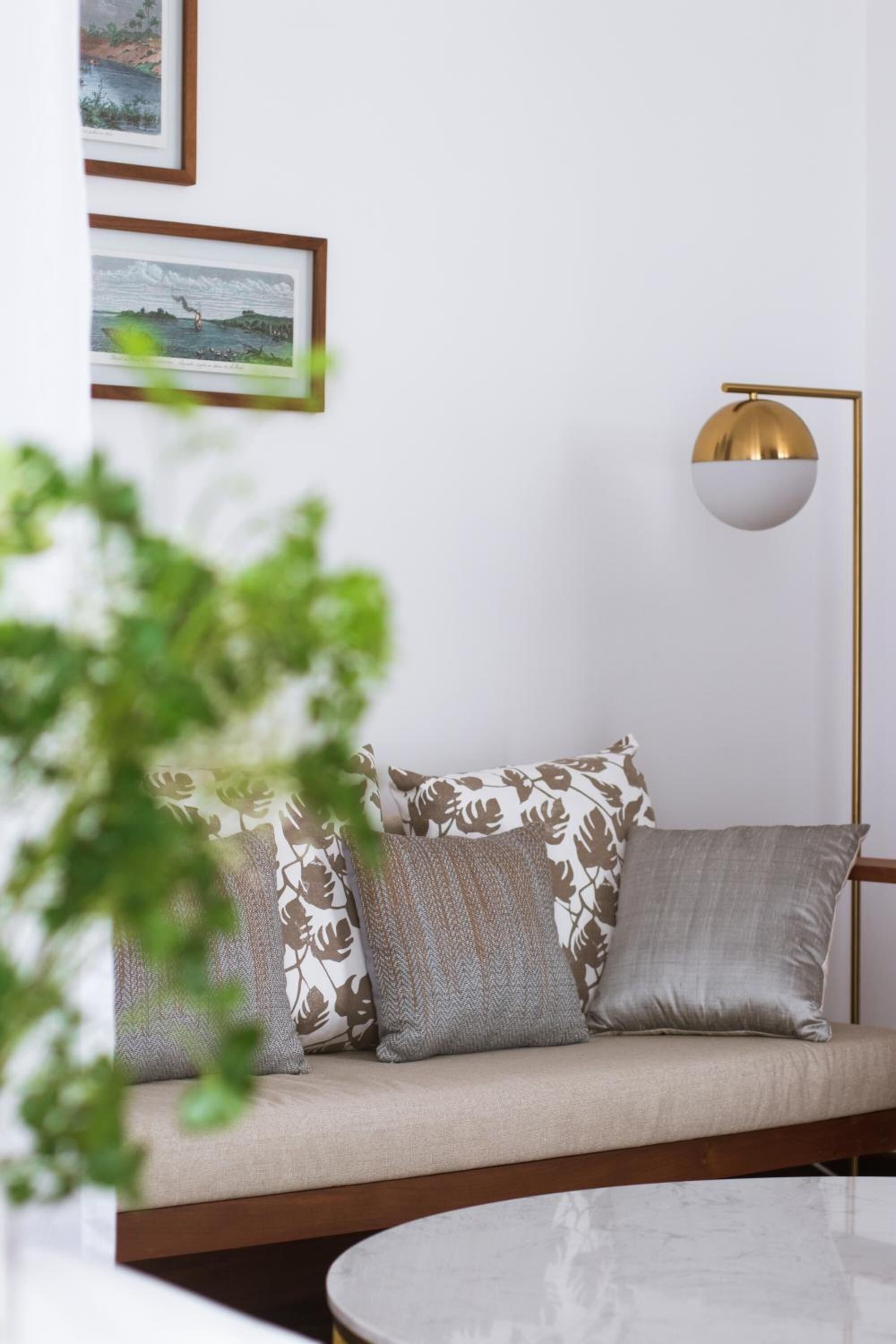 A modern living room with a sofa, cushions, a floor lamp, and framed artwork on the wall.