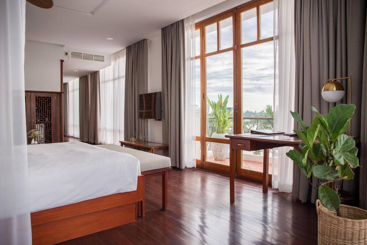 Ein modernes Hotelzimmer mit einem großen Bett, einem Schreibtisch und Blick ins Freie.