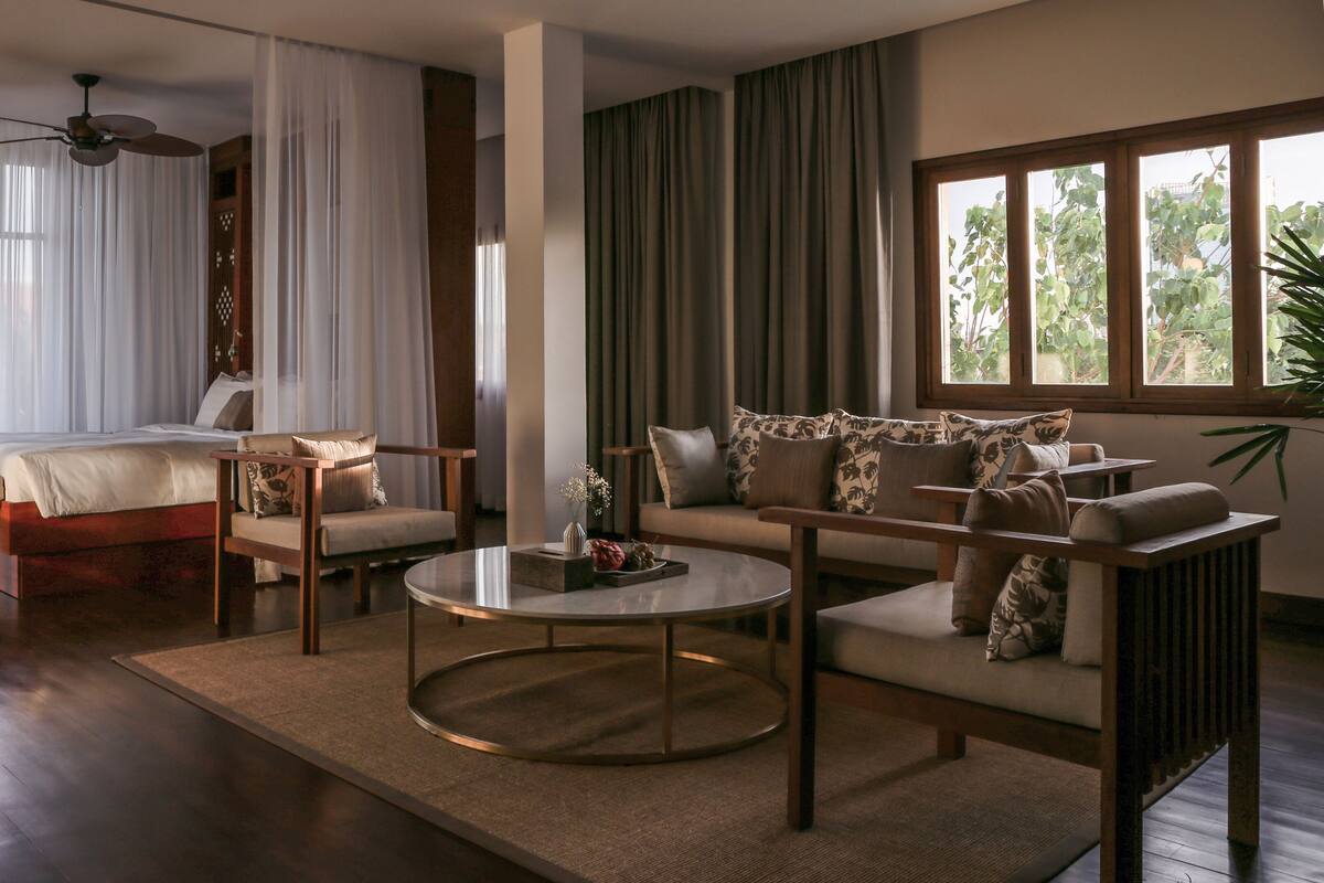 Ein geräumiges Zimmer mit einem Bett, einem Schlafsofa, einem Couchtisch und Blick auf die Stadt durch große Fenster.