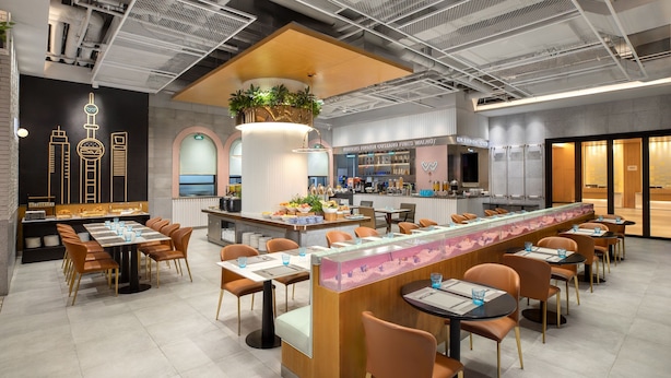 Un restaurante moderno con una barra alargada, varias zonas de estar y un bar.