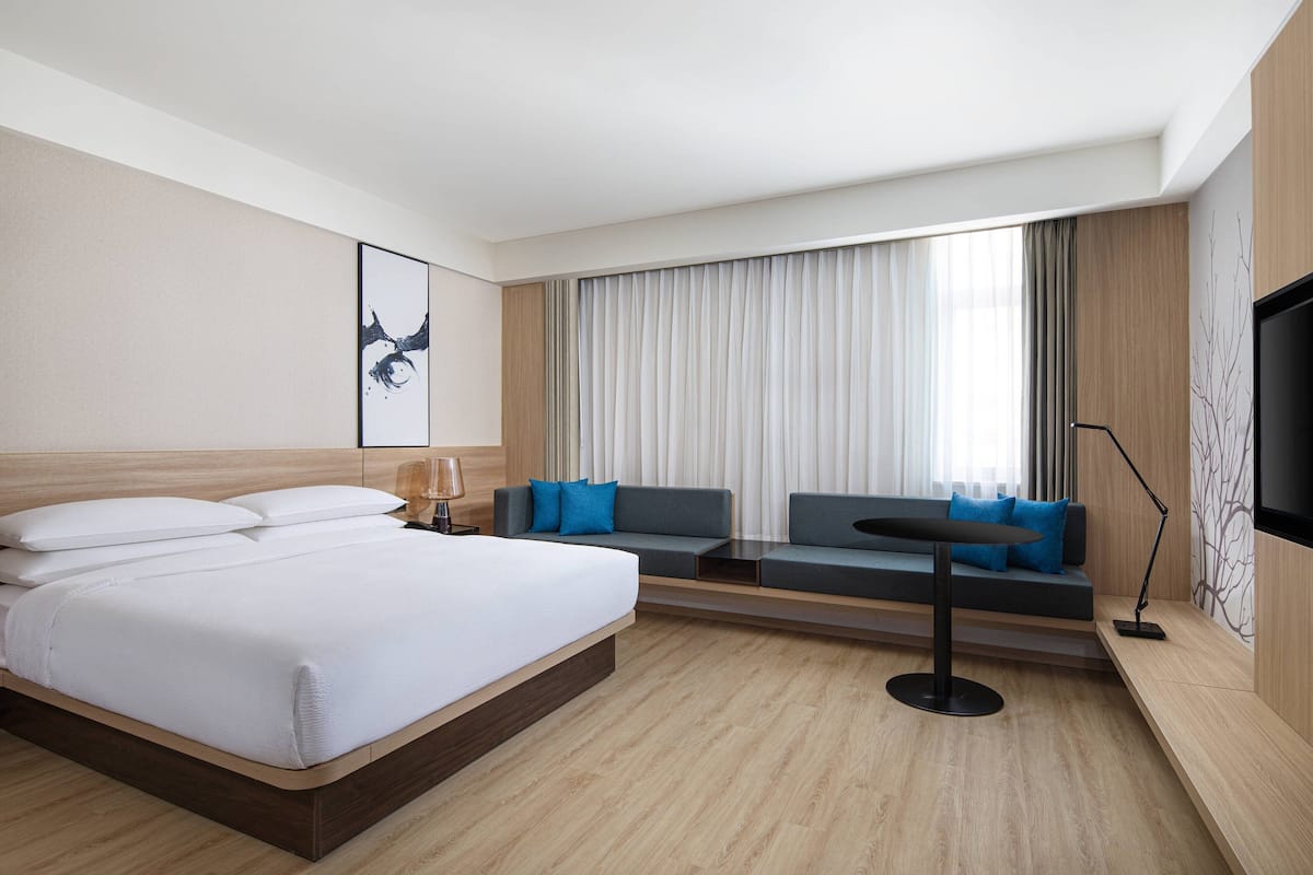 Une chambre d’hôtel moderne avec un grand lit, un canapé, une petite table et un téléviseur.