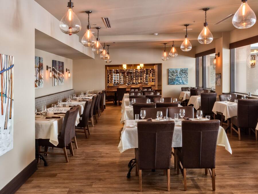 Un restaurante con varias mesas y sillas, lámparas colgantes y obras de arte en las paredes.