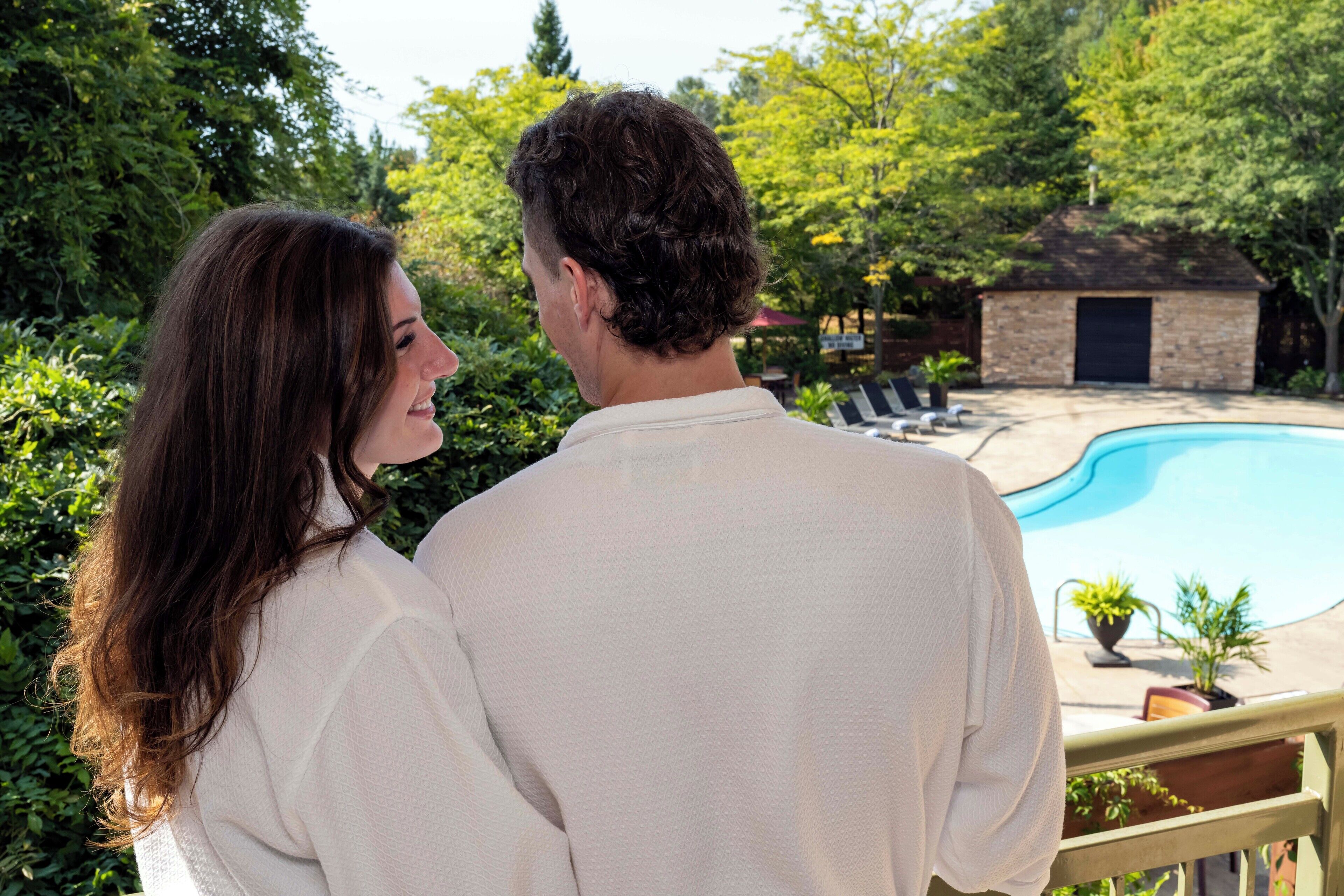 A couple standing by a pool with a stone building in the background.