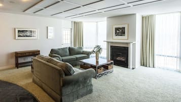 A living room with a fireplace, two sofas, a coffee table, and a carpeted floor.