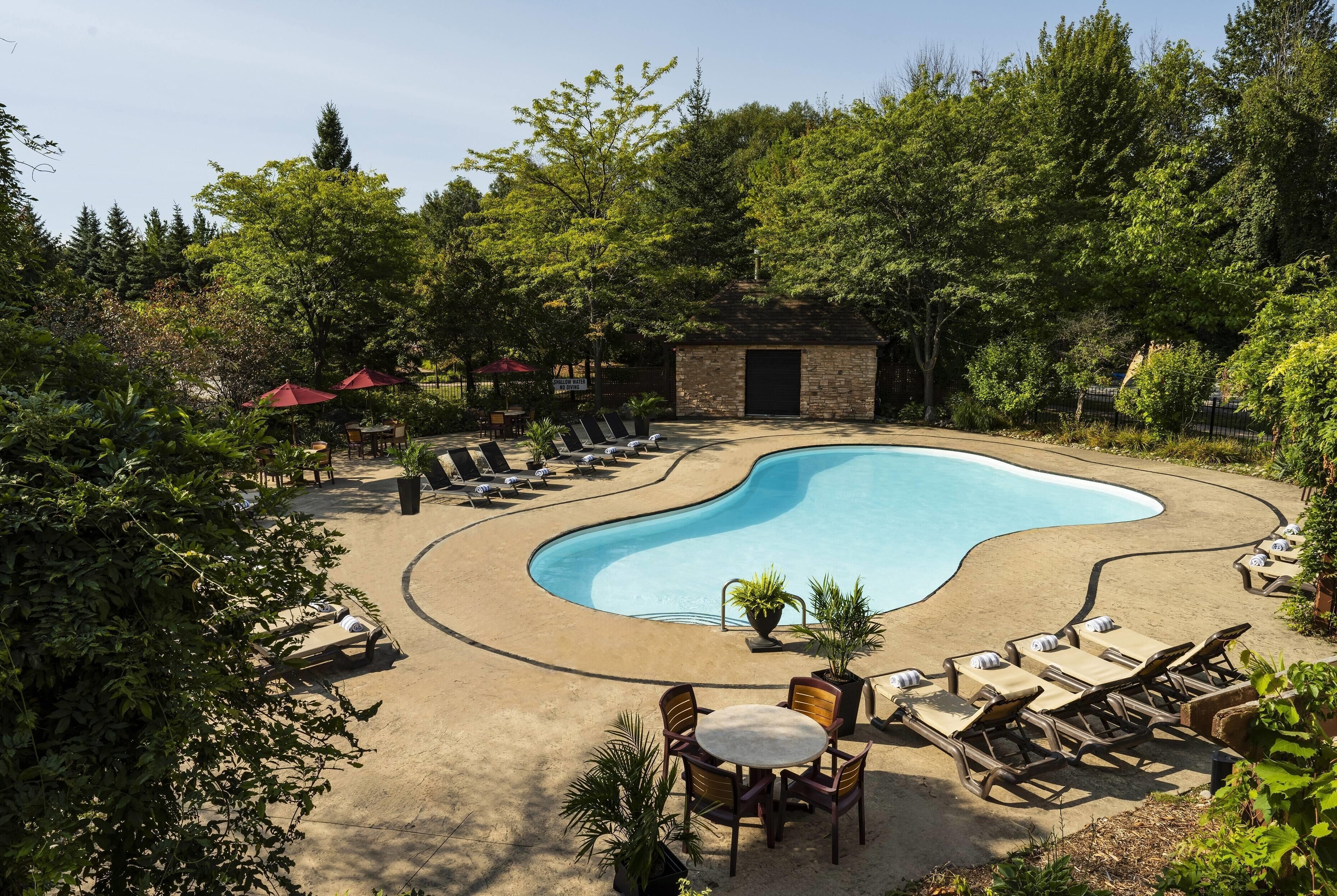 Une piscine avec des chaises longues et un petit bâtiment en pierre, le tout situé dans un espace aménagé.