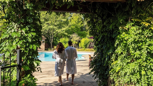Una pareja caminando hacia un área de piscina rodeada de abundante vegetación.