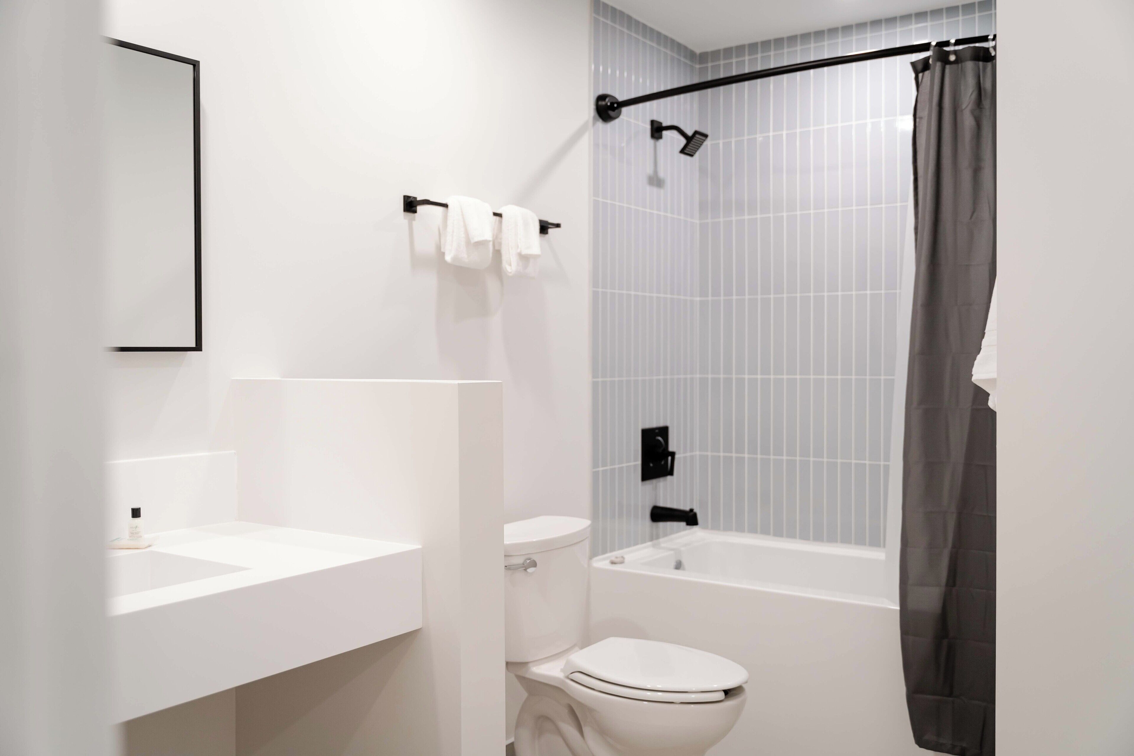 A modern bathroom with a white sink, toilet, and bathtub.