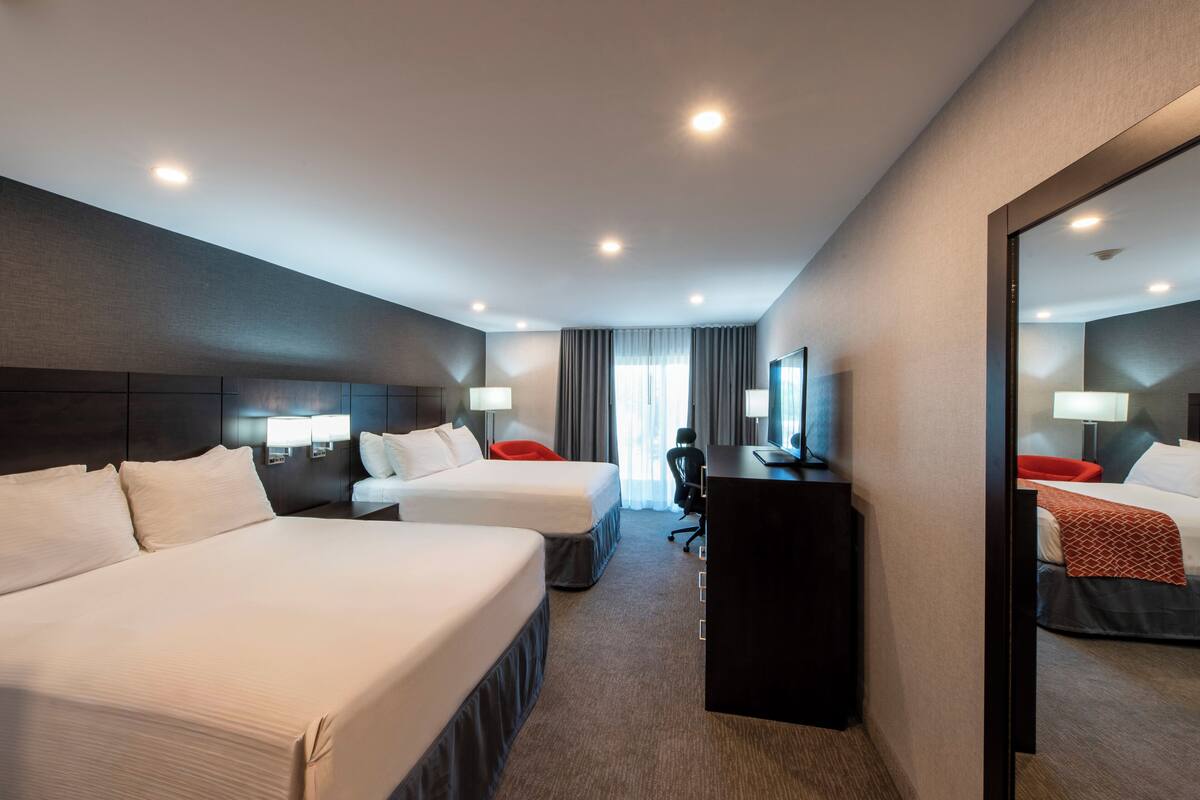 Een hotelkamer met twee bedden, een bureau, een stoel en een grote spiegel.