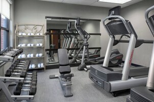 Un gimnasio con cintas de correr, mancuernas y máquinas de pesas.