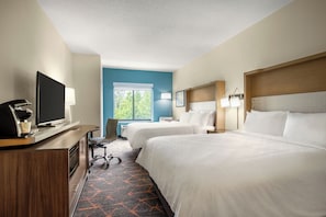 A hotel room with two beds, a desk with a TV, a chair, and a window with a view of greenery. - Holiday Inn Cheshire - Southington by IHG (Southington)