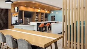 A modern restaurant with a wooden bar area, a long table with chairs, and a menu board. - Holiday Inn Cheshire - Southington by IHG (Southington)