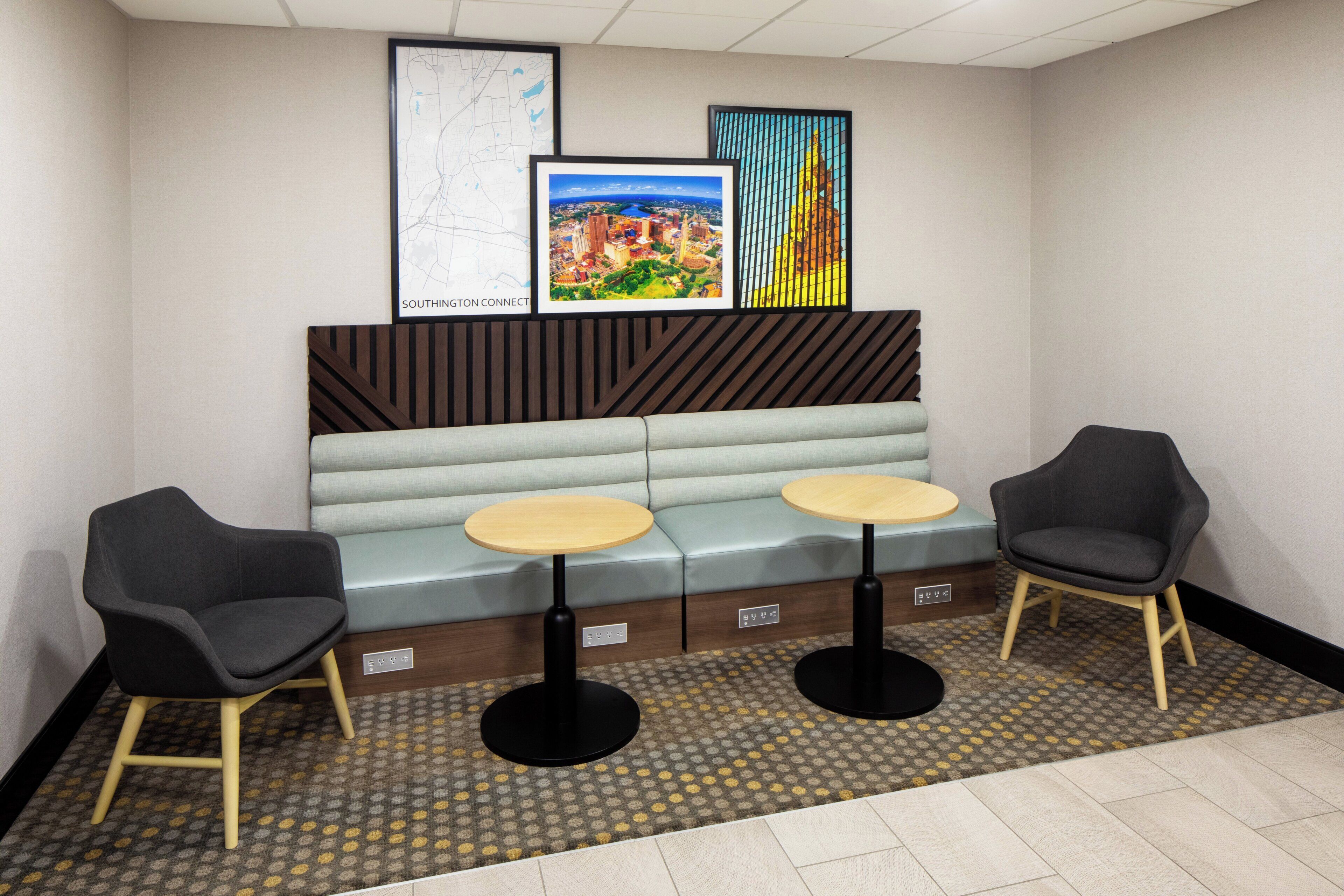 A seating area with two tables and chairs, a bench, and framed artwork on the wall.
