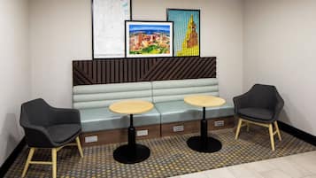 A seating area with two tables and chairs, a bench, and framed artwork on the wall.