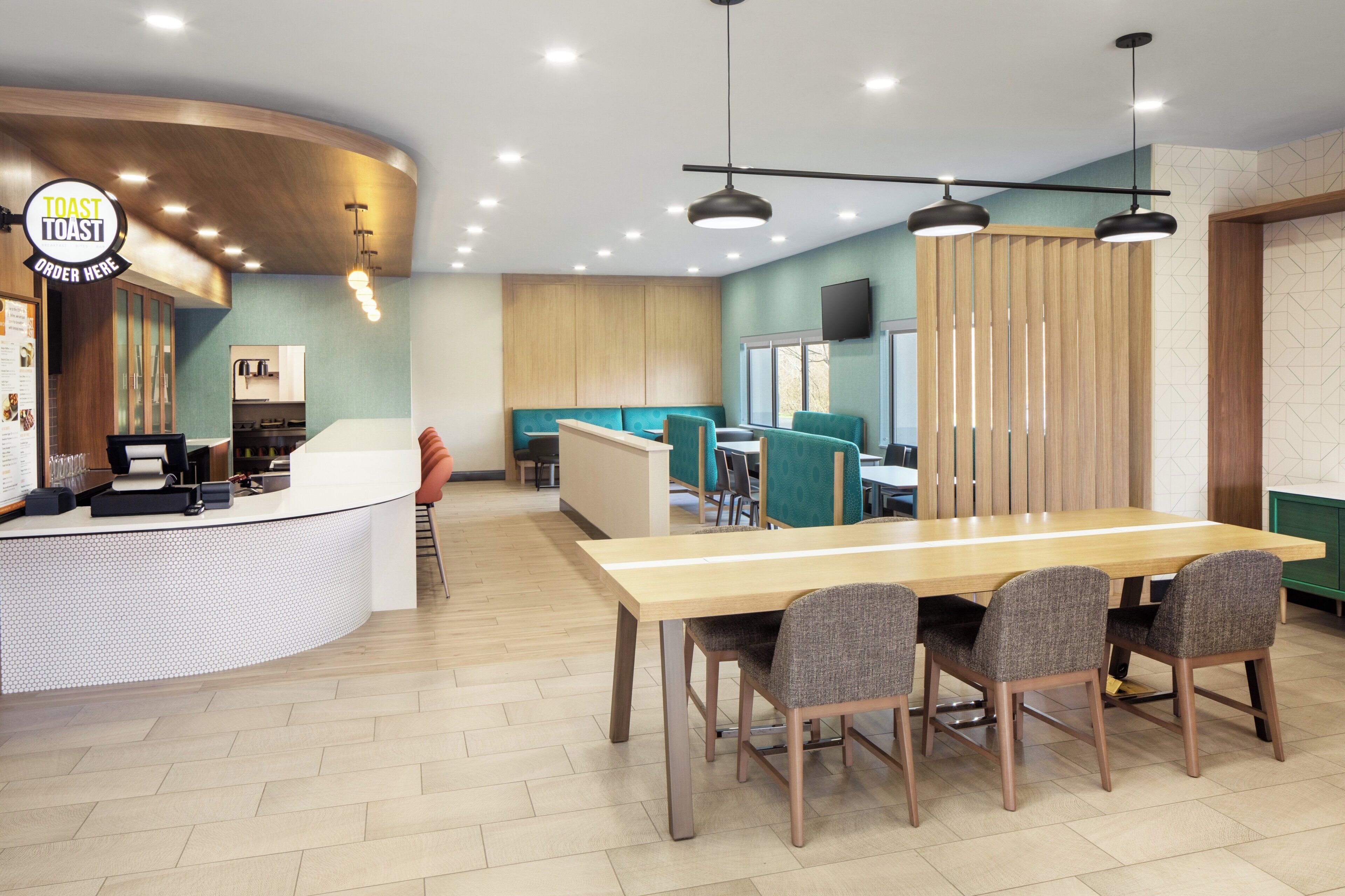 A modern restaurant interior with a counter, seating area, and a dining table.