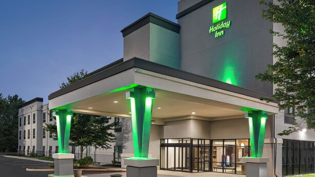 A Holiday Inn hotel with a covered entrance and green lighting. - Holiday Inn Cheshire - Southington by IHG (Southington)