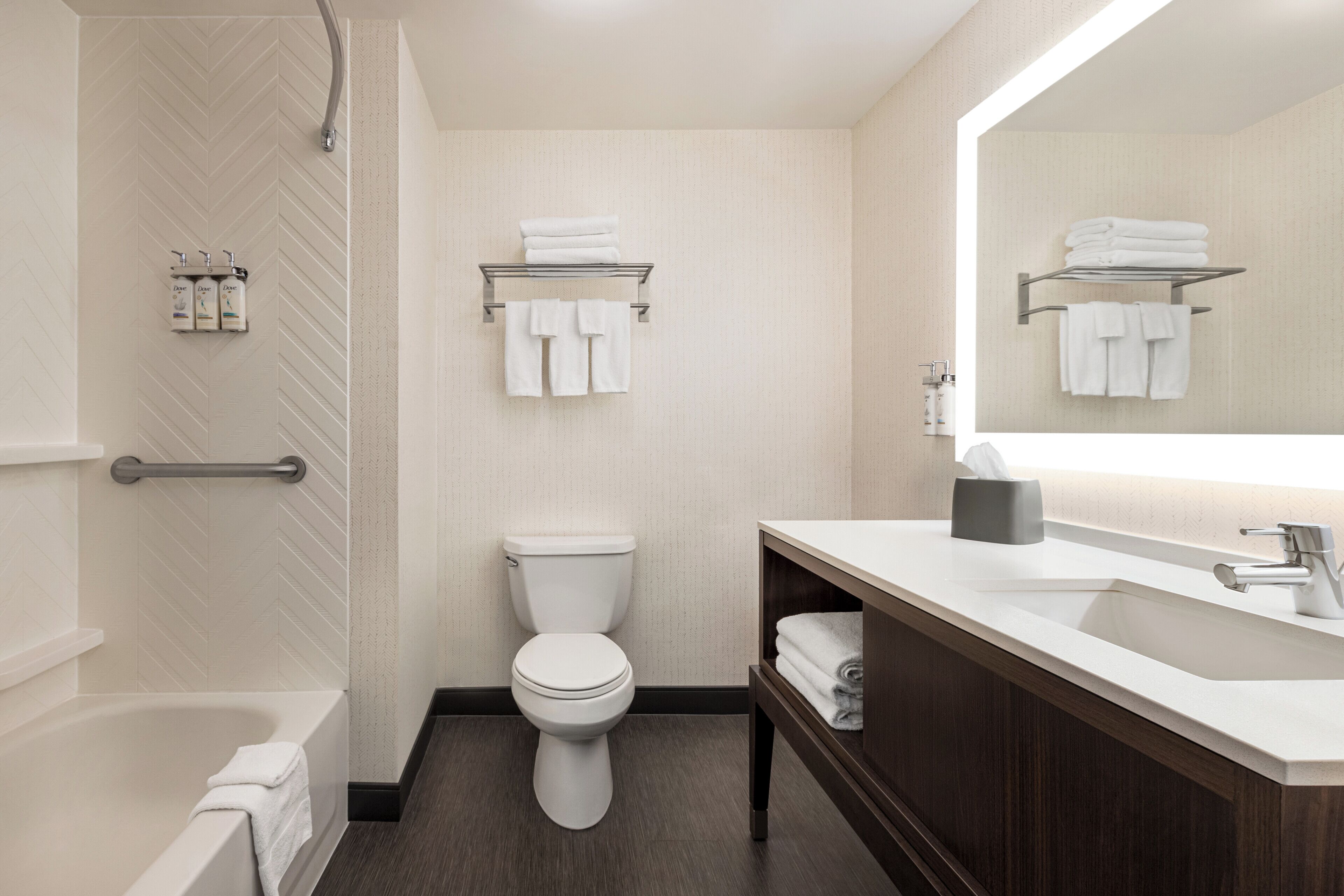 Une salle de bain moderne équipée d’une baignoire, de toilettes et d’un meuble-lavabo avec un miroir.
