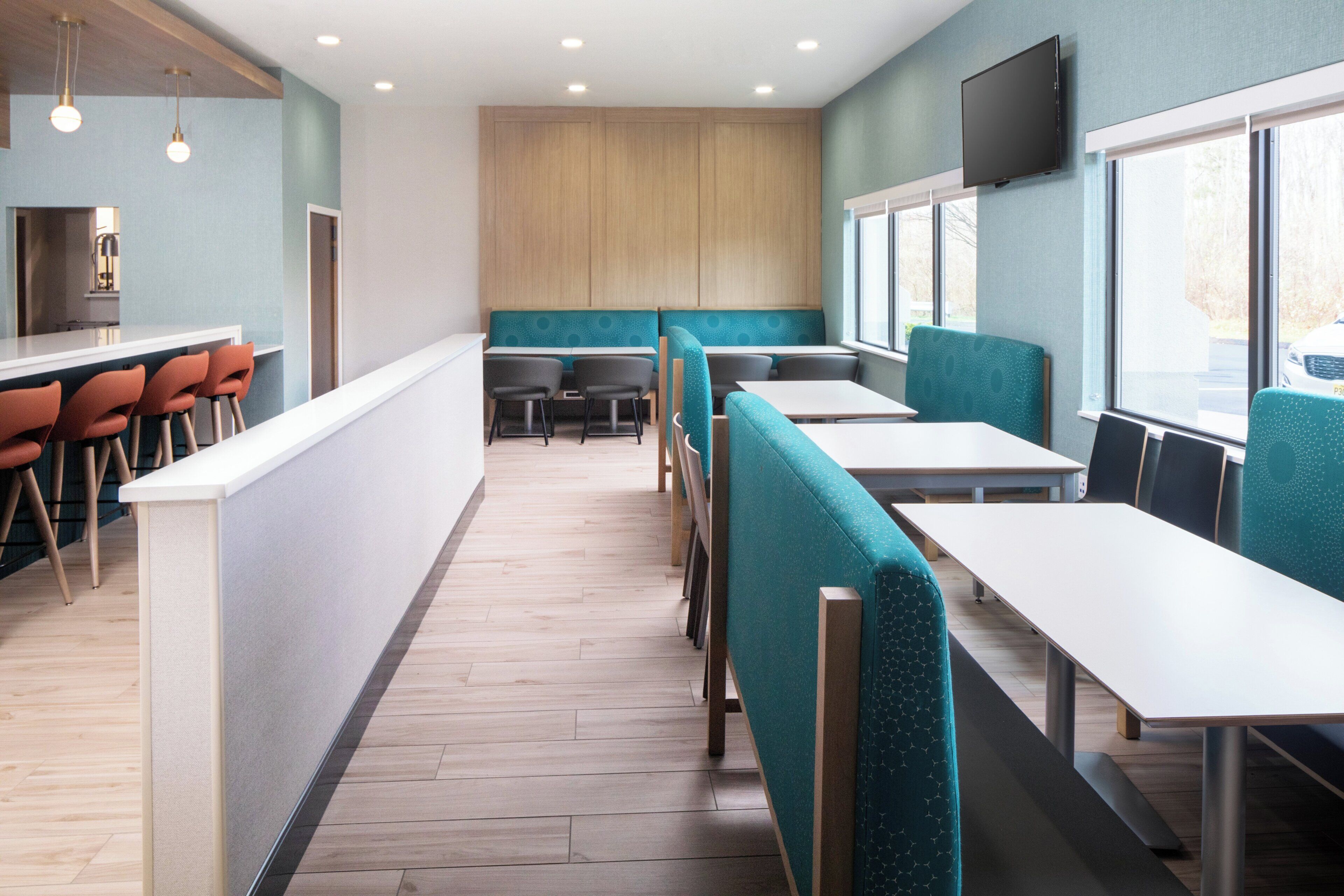 Un intérieur de restaurant moderne avec un comptoir, des places assises et un téléviseur.