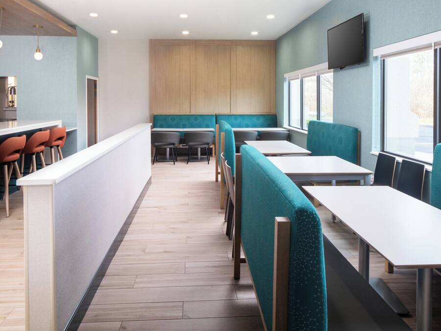A modern restaurant interior with a counter, seating, and a television.